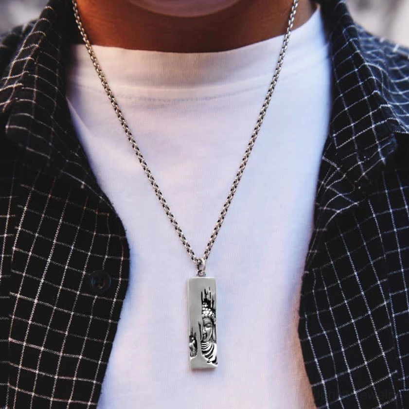 Buddhist pendant necklace worn on model - silver Buddha relief with thin metal chain styled with casual checkered coat