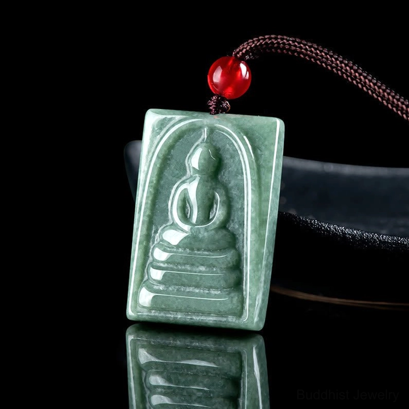 Side-overhead shot of jade Buddha amulet on dark holder, showing depth of hand-carved Buddha relief