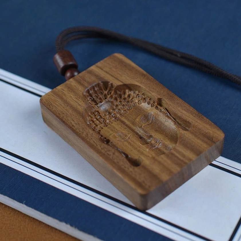Reverse side of handcarved green sandalwood Buddha pendant necklace displaying intricate back carving on black rope cord