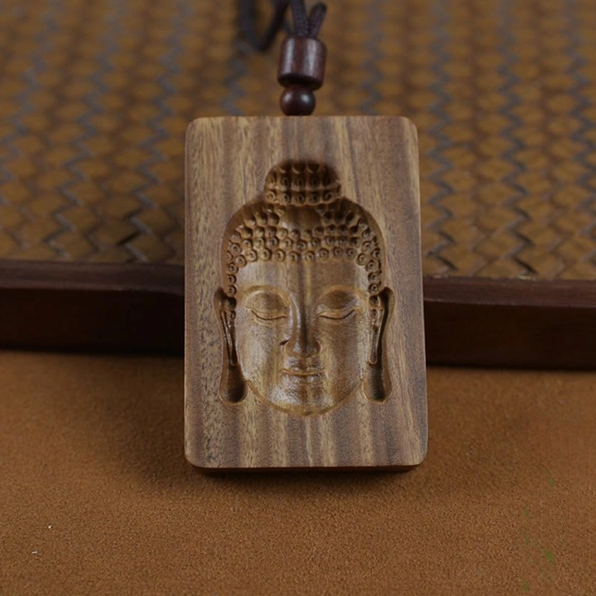 Square carved green sandalwood Buddha pendant showing embossed Buddha head design with dark wooden bead accent on natural rope necklace