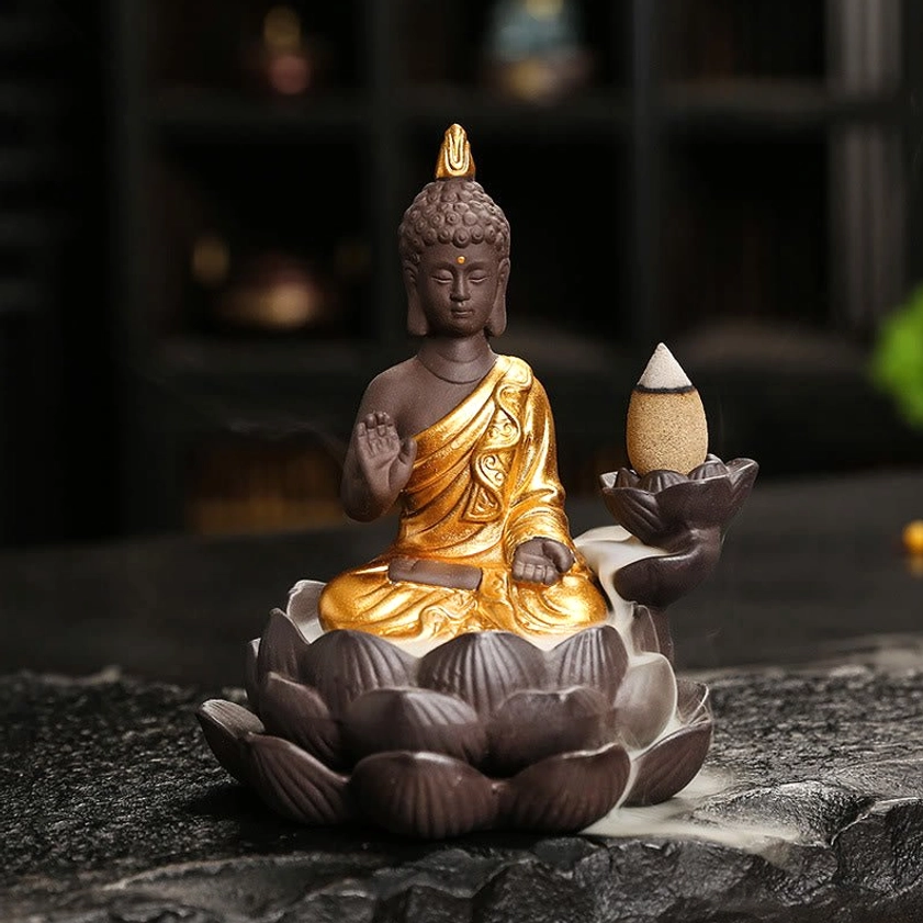 Buddha backflow incense burner with prayer blessing mudra gesture and gilded ceramic robe on dark stone surface