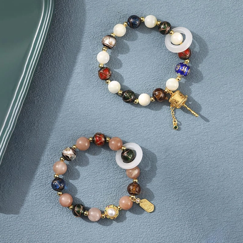 Two handmade Buddhist prayer bracelets with sun stone and tridacna stone beads, featuring gilt metal prayer wheel charms