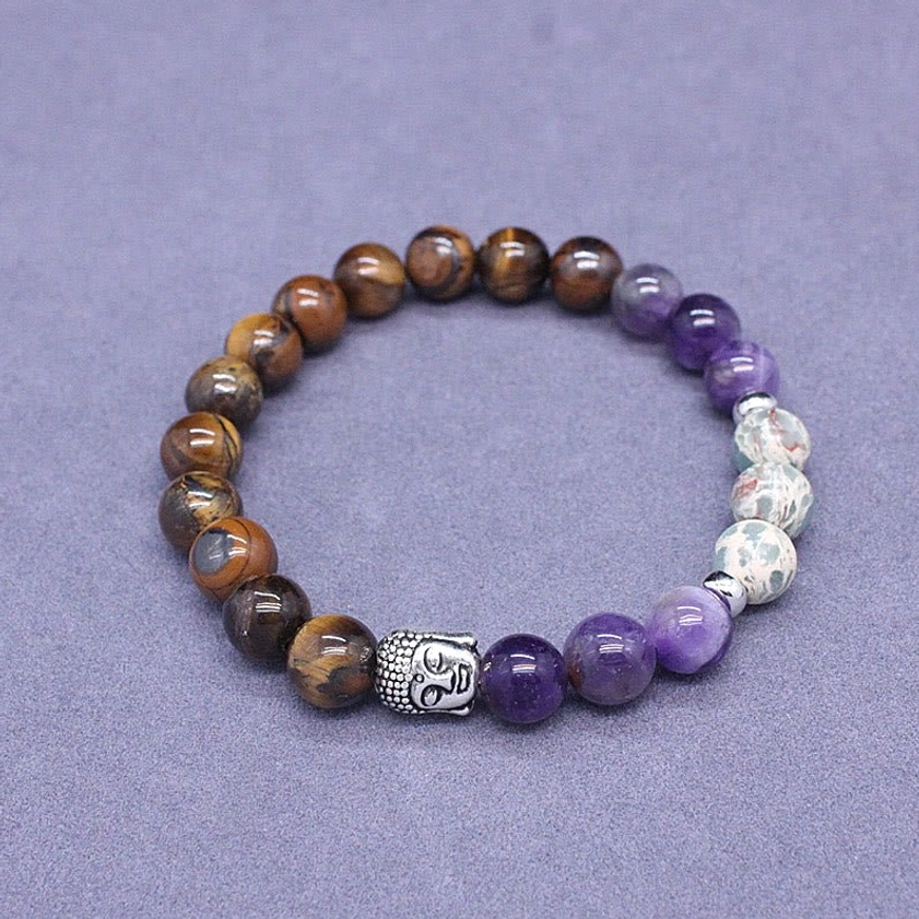 Top-down flat lay of mixed gemstone Buddha bracelet on purple fabric with tiger eye and agate beads