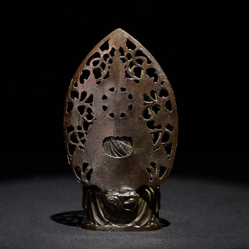 Buddha statue rear view showing hollowed floral back panel with central opening and weathered bronze tone