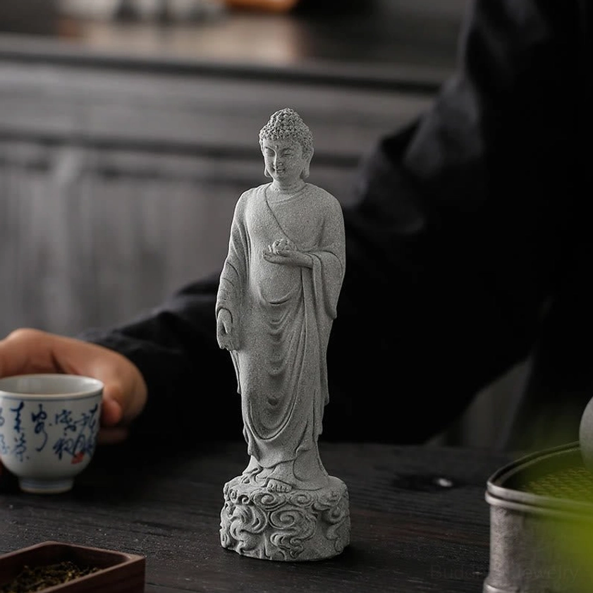 Buddha statue with ceremonial bowl displayed on table with tea ceremony porcelain