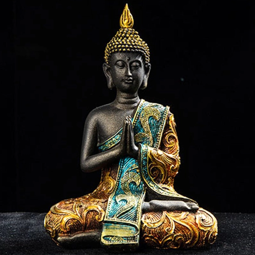 Detailed close-up of hand-carved Buddha statue showing ornate gold-teal embroidered robe with swirling patterns and prayer hand mudra