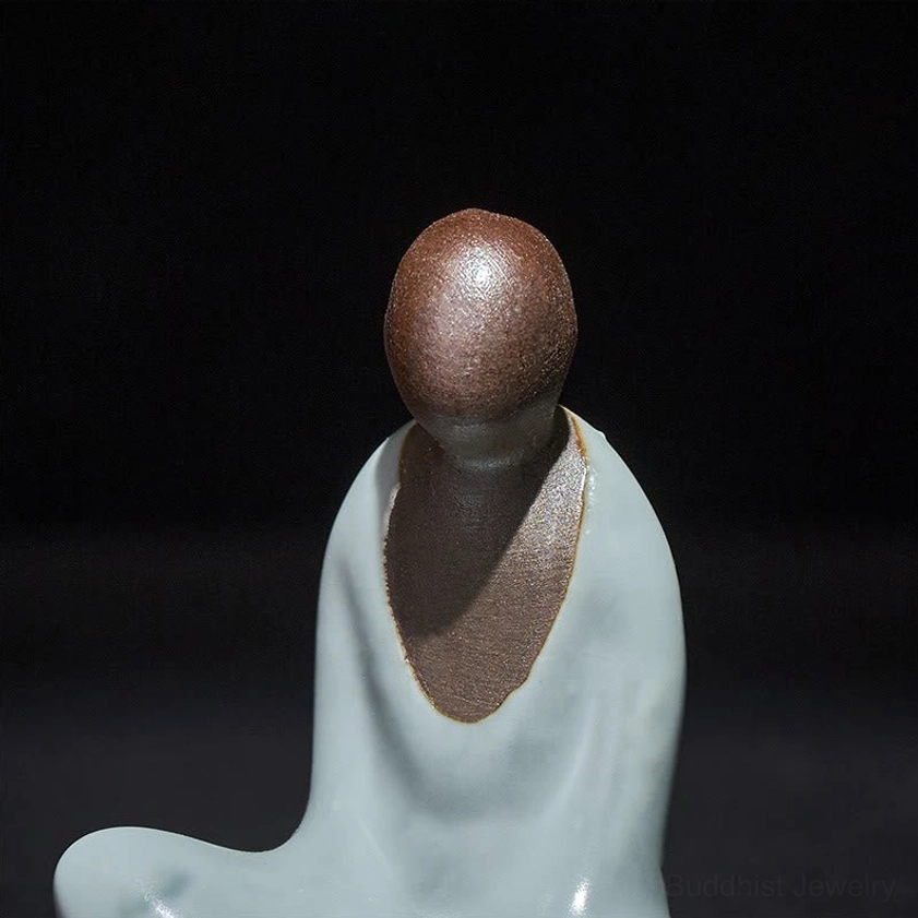 Close-up detail of handcrafted ceramic Buddha statue showing glazed texture and brown base