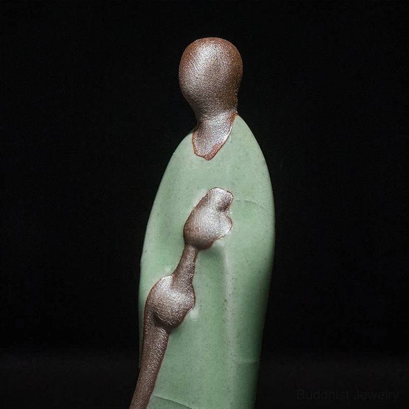 Close-up detail view of handmade Buddha ceramic statue showing crackle glaze texture bronze broom and serene craftsmanship