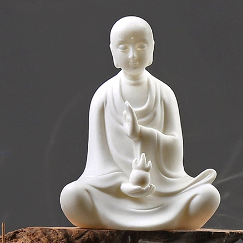 Close-up detail view of handcrafted ceramic Buddha statue showing serene facial features and smooth matte white texture