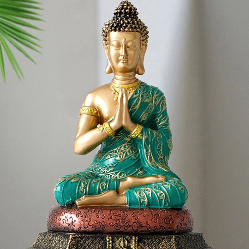 Close-up detail of Buddhist statue showing teal robe embroidery and fine golden carving on figure