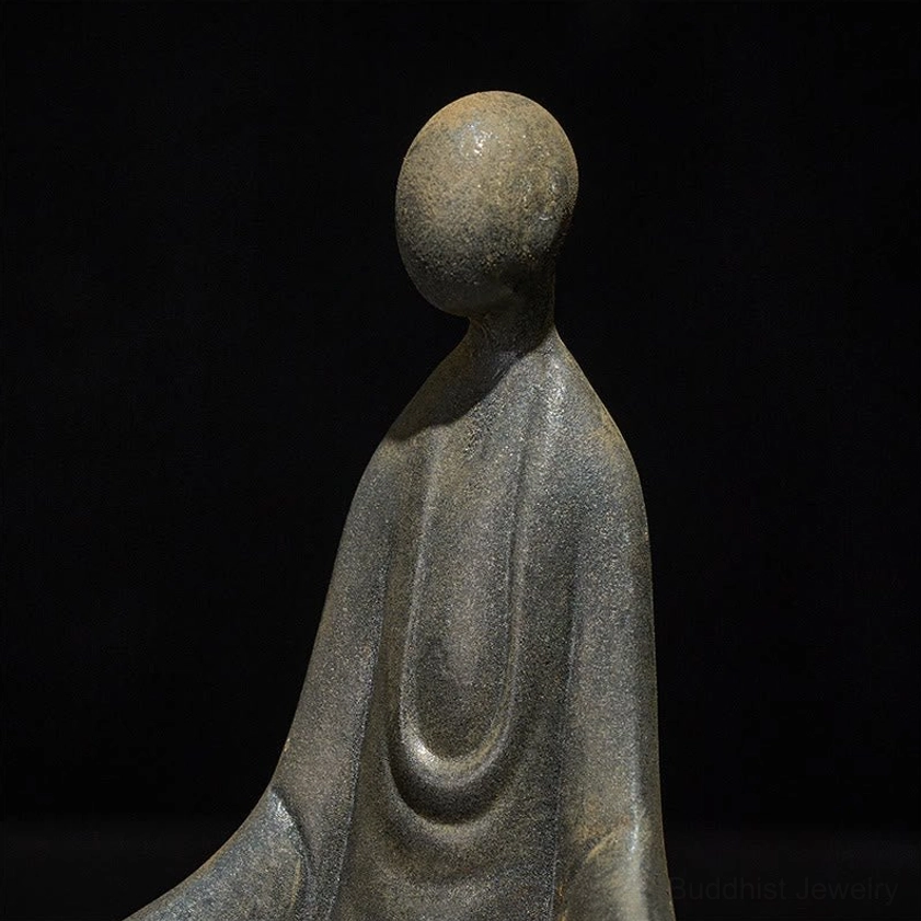 Close-up rear side view of formless Buddha sculpture showing smooth head and intricate robe folds detail