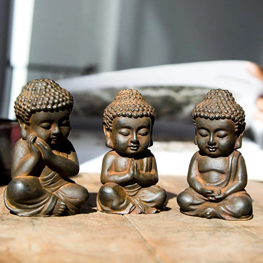 Seated baby Buddha figurines with different hand gesture mudras - front eye-level view wooden table
