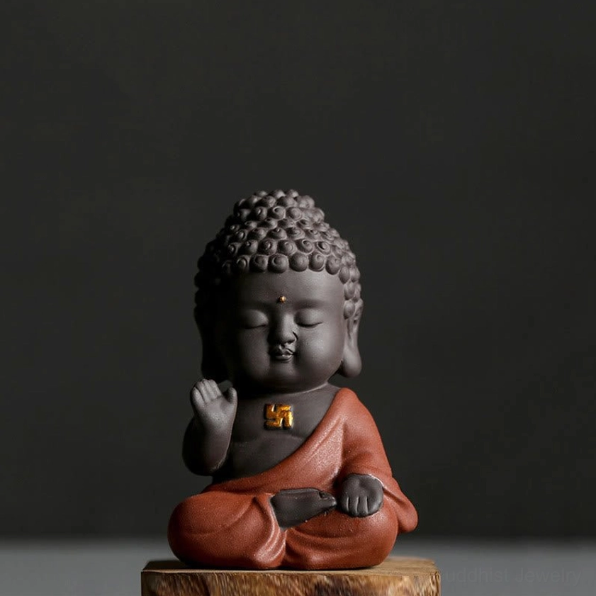Front view of handcrafted Buddha statue featuring golden swastika emblem on chest, cross-legged meditation pose on wooden base