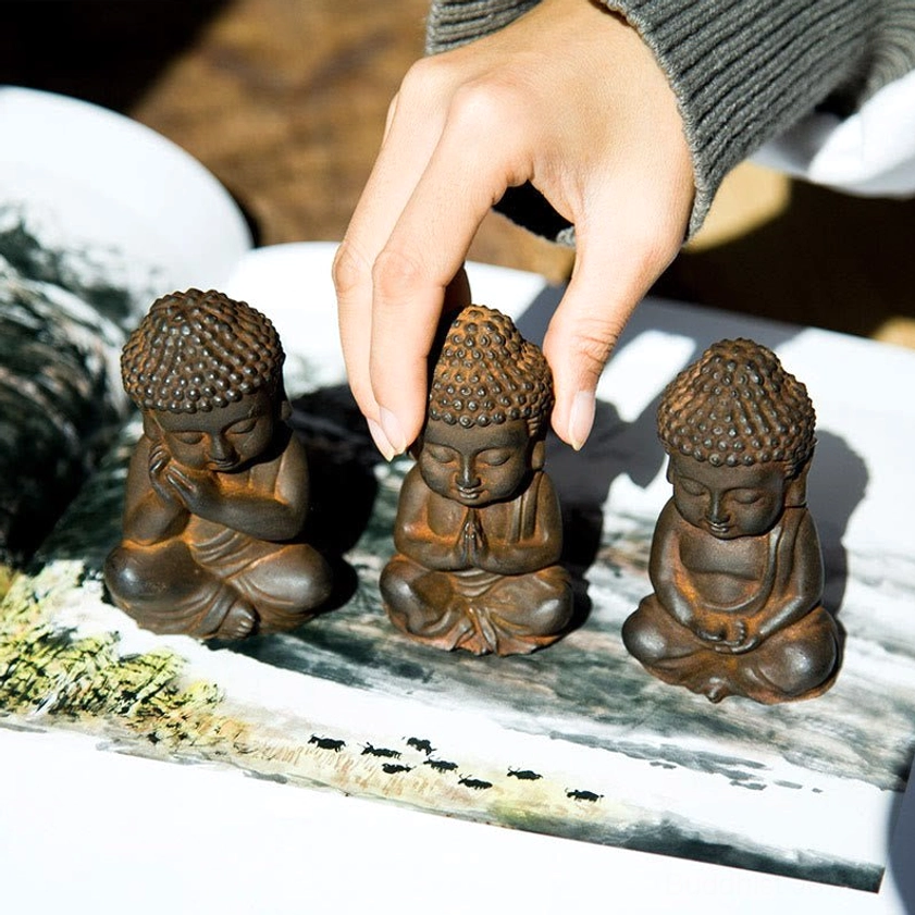 Hand adjusting handcrafted Buddha figurine on chinese painting mat background - meditation statue detail