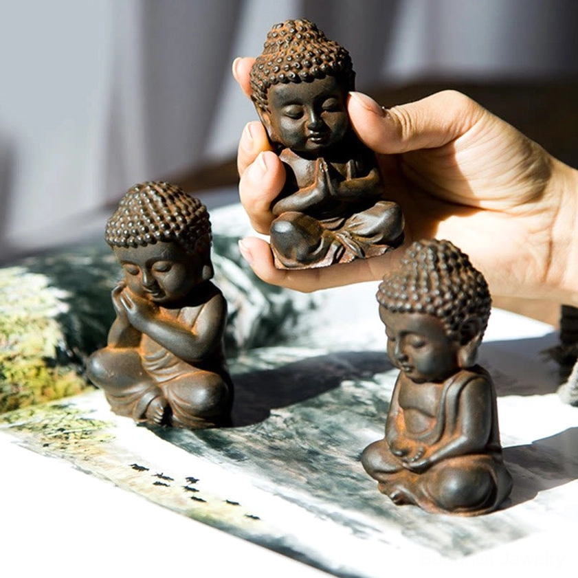 Buddha figurine held in hands with landscape painting tabletop - rustic textured brown finish close-up