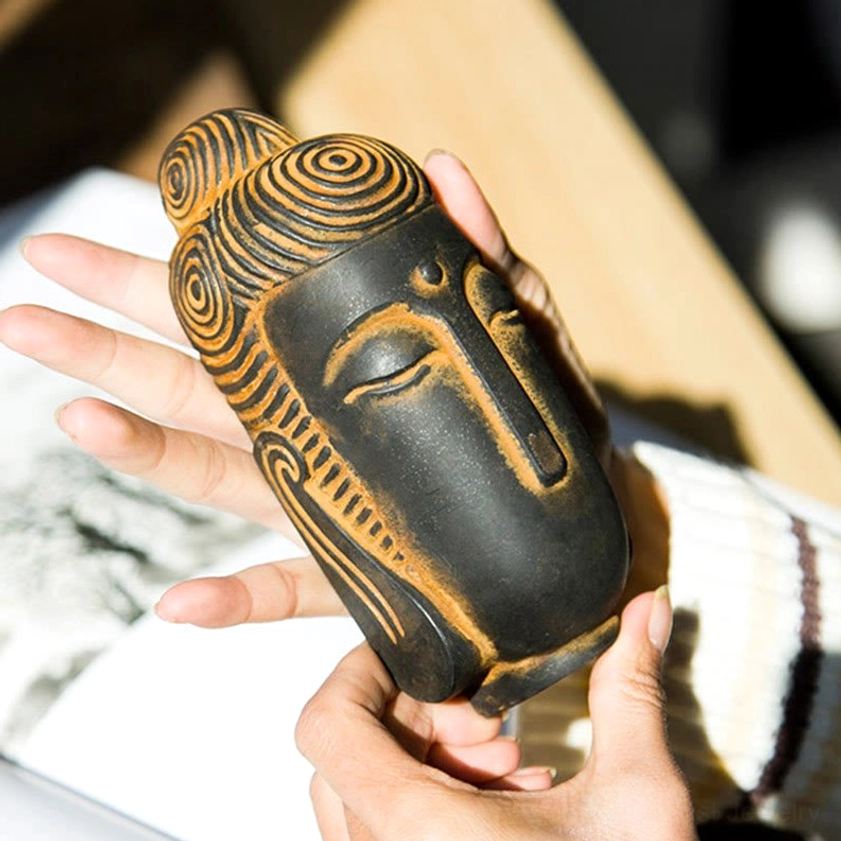 Handcrafted meditating Buddha statue held in hands showing carved hair details and rusty accents