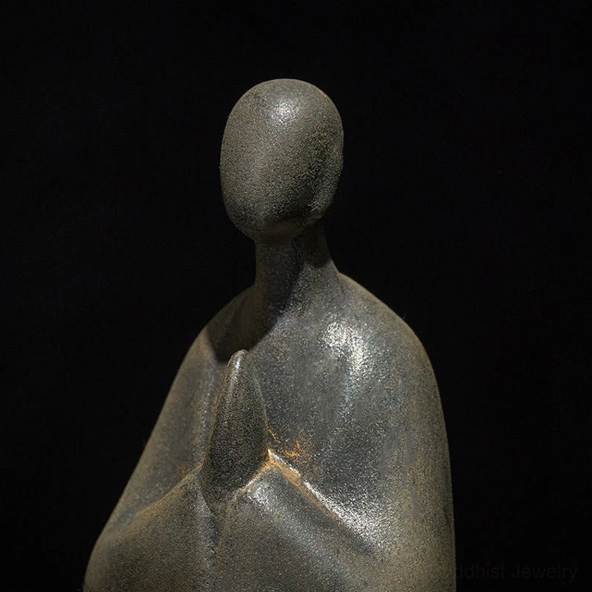 Close-up detail of Buddha statue head and hands in prayer, featureless serene expression