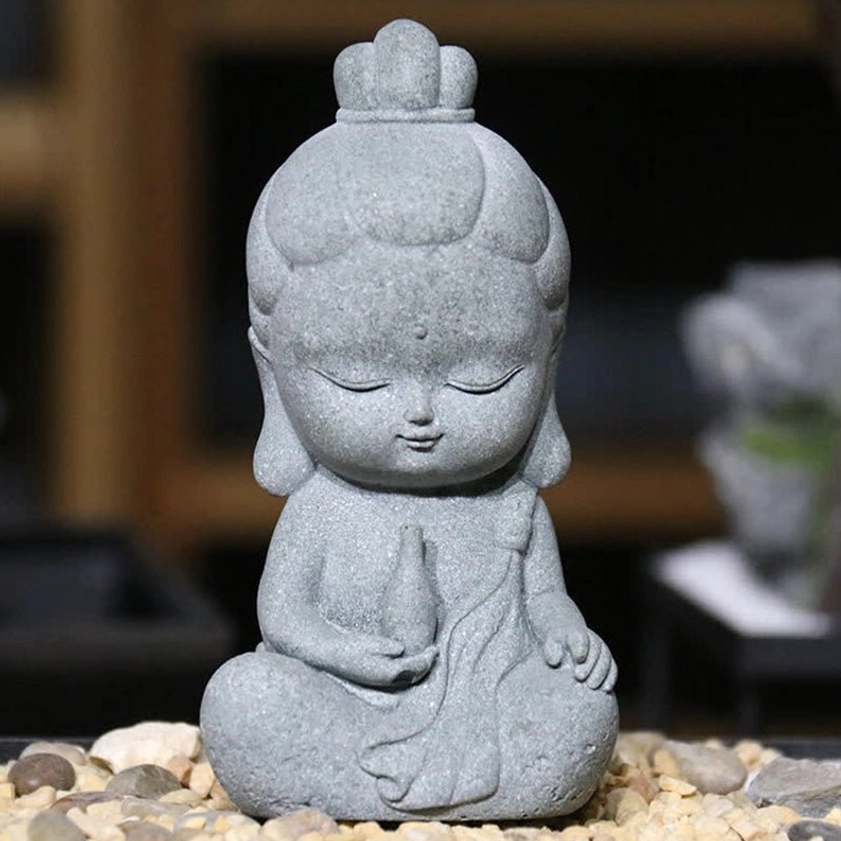 Mini Buddha statue holding small vase with closed eyes, dark grey stone texture, symbol of compassion and inner peace home decor