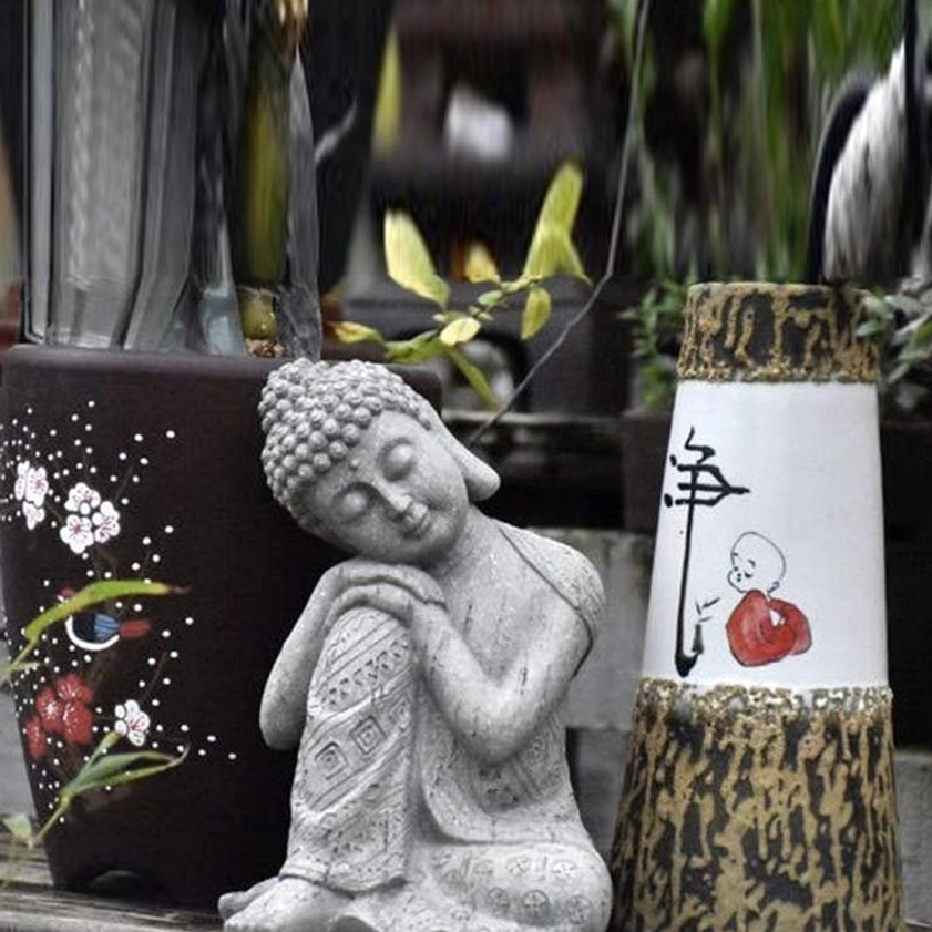Handcrafted resin Buddha figurine displayed beside hand-painted ceramic vases and pots