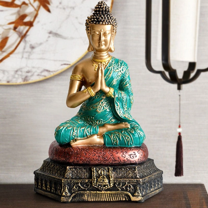 Buddha meditation statue displayed in home interior setting with wall hanging and warm pendant lamp lighting