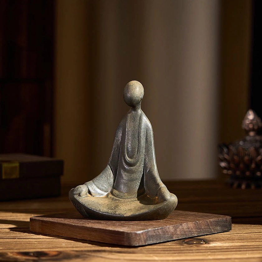 Left front three-quarter view of small meditating Buddha decor with detailed robe drapery on wooden table