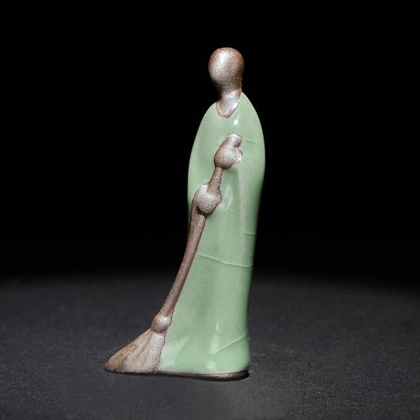 Formless Buddha sweeping monk handmade ceramic figurine left profile studio photography pure black background
