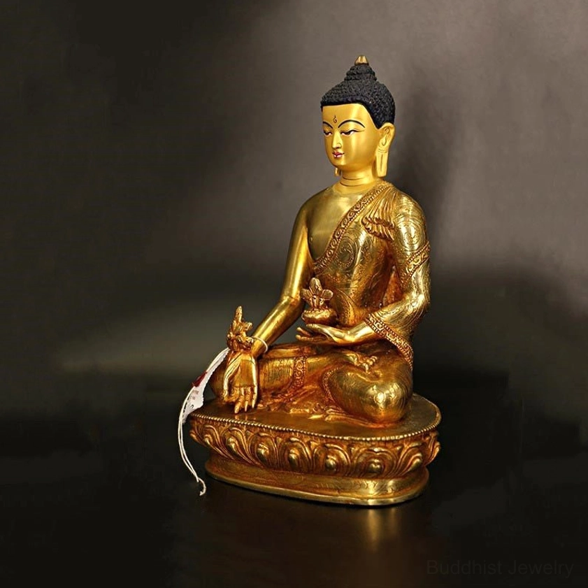 Left three-quarter view of gilt bronze Buddha statue holding ritual implements, smooth polished golden surface