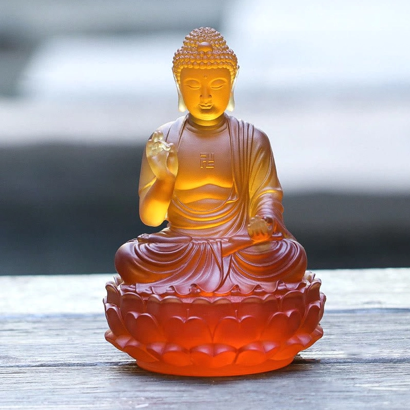 Handcrafted Liuli crystal Buddha statue direct front view with warm amber-red glaze finish and traditional monk robes