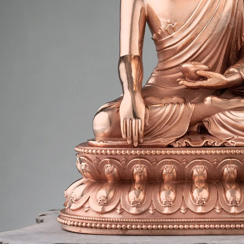 Close-up detail of Buddha statue lower torso and carved lotus base with draped monk robes