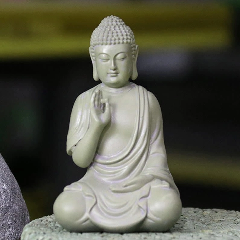 Close-up meditation Buddha resin statue showing detailed facial features, serene expression, and cross-legged sitting pose on dark background