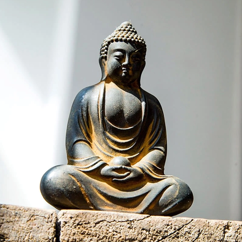Close-up meditating Buddha statue with ushnisha headpiece, weathered dark grey, dharma mudra hands gesture detail