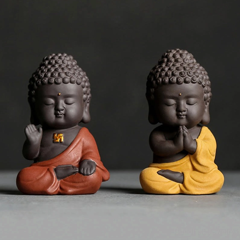 Two small Buddha figurines with curly hair, red and yellow robes, front view on dark grey background, handcrafted purple clay meditation statues