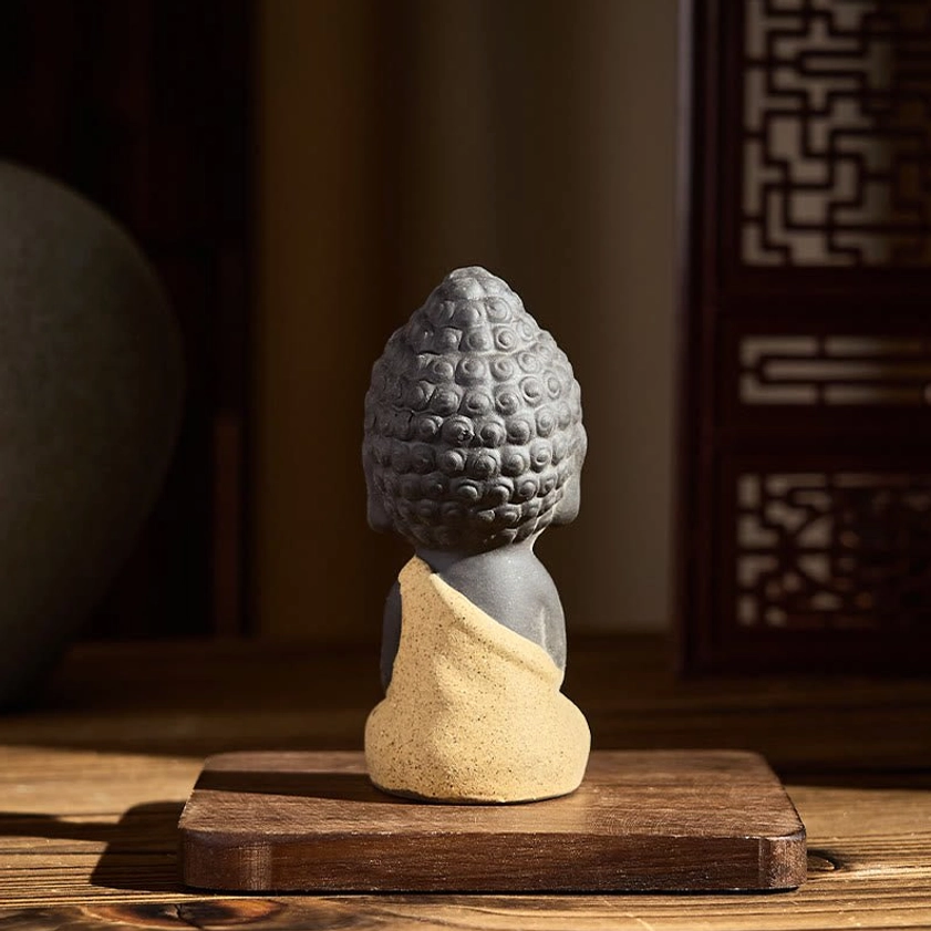 Rear view of yellow robed Buddha statue showing back curly hair and robe details, purple clay artisan craft