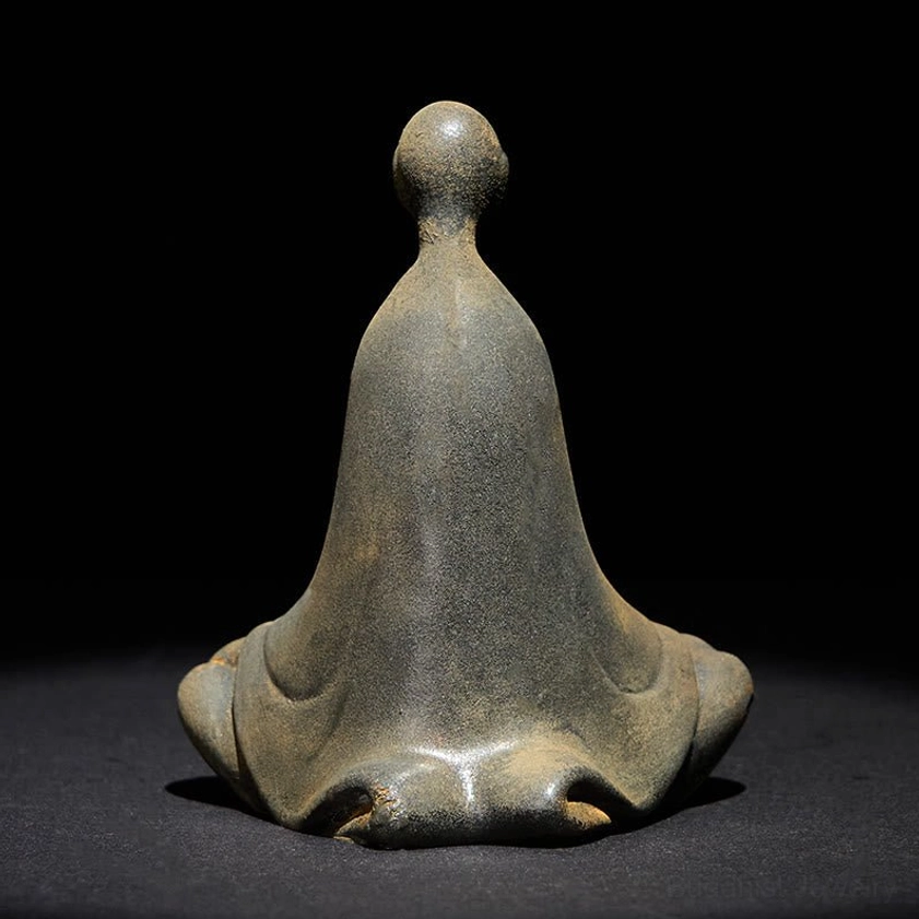 Rear view of sitting Buddha statue showing back of robes and smooth rounded head meditating pose
