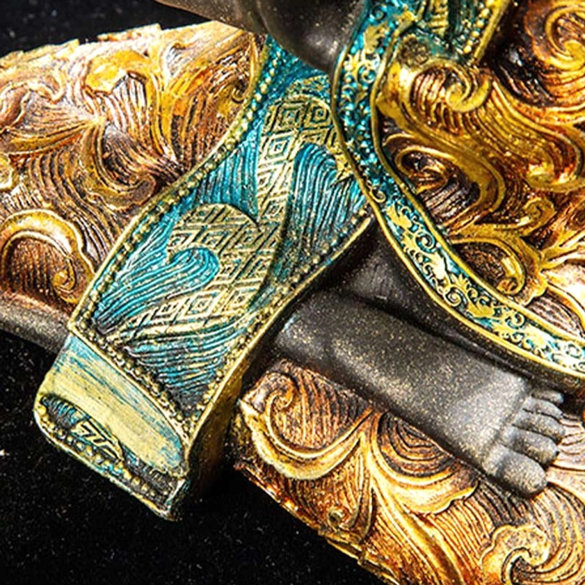 Macro close-up detail of Buddha statue's embossed gold swirling patterns and teal geometric fabric trim with vintage distressed finish