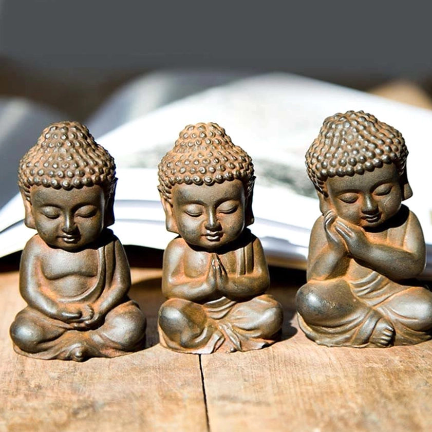 Handmade Buddha figurines displayed on wooden desk with book - rustic vintage brown texture