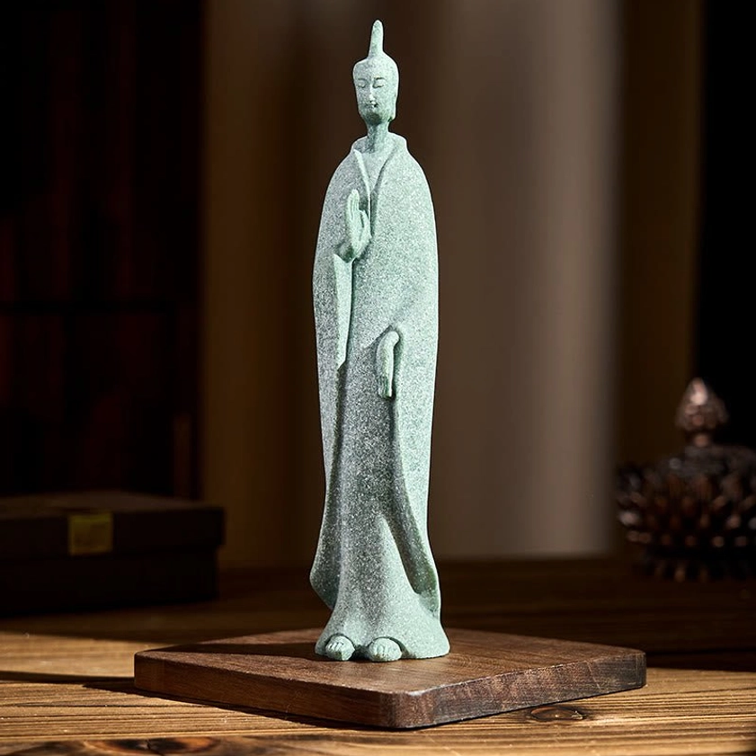 Standing Buddha sandstone figurine with natural stone texture and flowing robes on wooden table