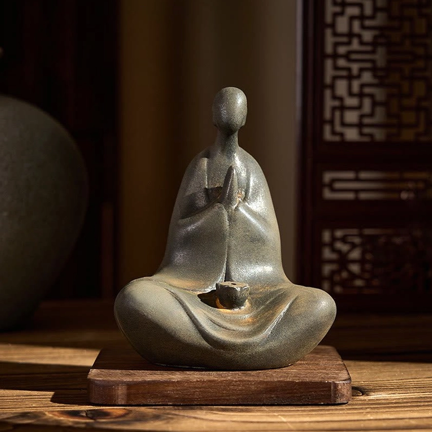 Handcrafted Buddha statue side angle view on wooden coaster, weathered grey-brown rustic finish