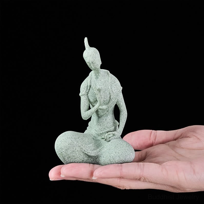Handcrafted Buddha statue held in human palm, demonstrating compact size, light green sandstone with fine texture