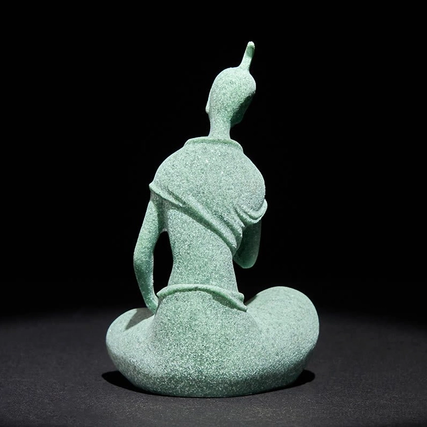 Buddha meditation statue held between fingertips, showing portable compact dimensions, coarse sandstone texture visible