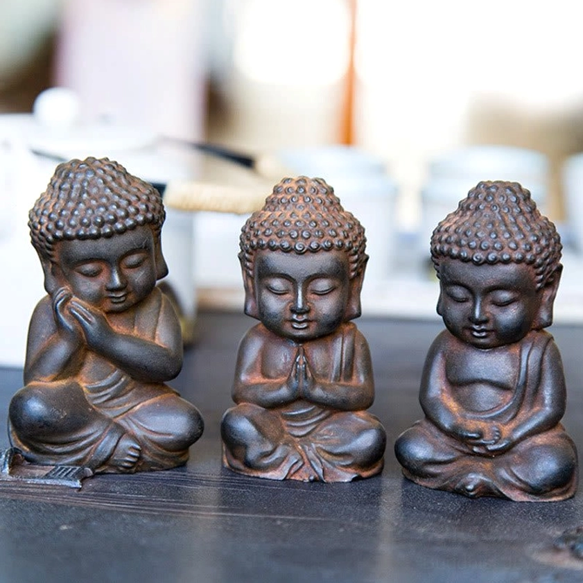 Buddha decoration set with tea ware blurred background - dark rusty brown textured finish sitting poses