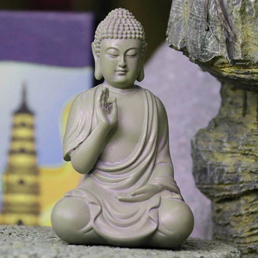 Front three-quarter view of meditation Buddha resin statue with soft ambient lighting, seated in contemplative pose with detailed robe draping