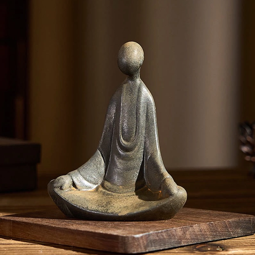 Three-quarter right view of handmade formless Buddha ornament showing robe drapery detail on warm wood table