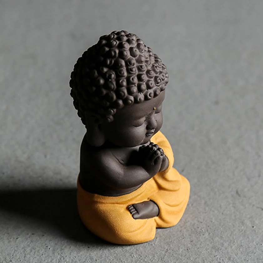 Small purple clay Buddha statue photographed in warm lighting, highlighting matte texture and peaceful spiritual presence