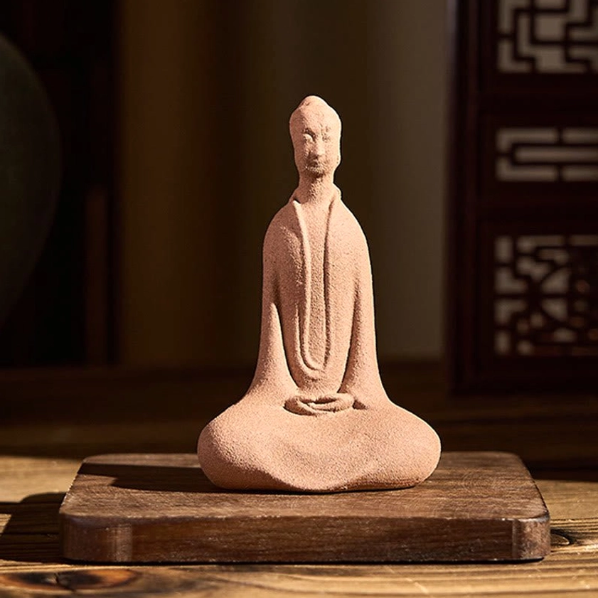Buddha statue displayed on traditional wooden base with Chinese-style indoor setting, light earthy ceramic with overhead angle view