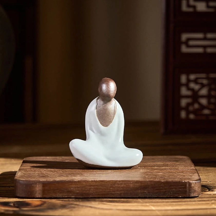 Small formless Buddha statue displayed on wooden coaster in traditional Asian home decor setting