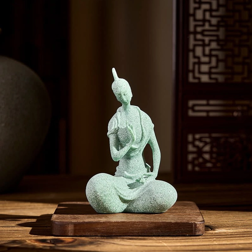 Buddha decorative statue displayed on wooden coaster, three-quarter view showing traditional posture and craftsmanship details