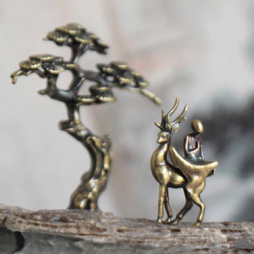Mini meditation Buddha statues set with miniature pine tree and deer companion on rock display, close-up showing detailed bronze metal craftsmanship