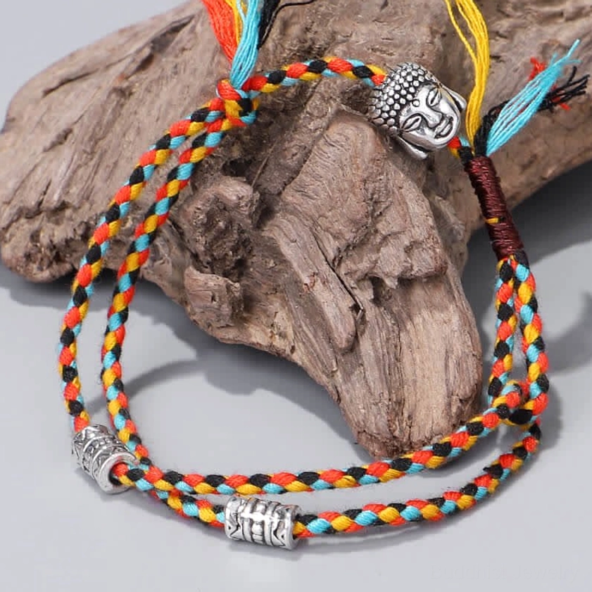 Buddha head string bracelets with red-blue-black braided cords on wooden surface, lifestyle display