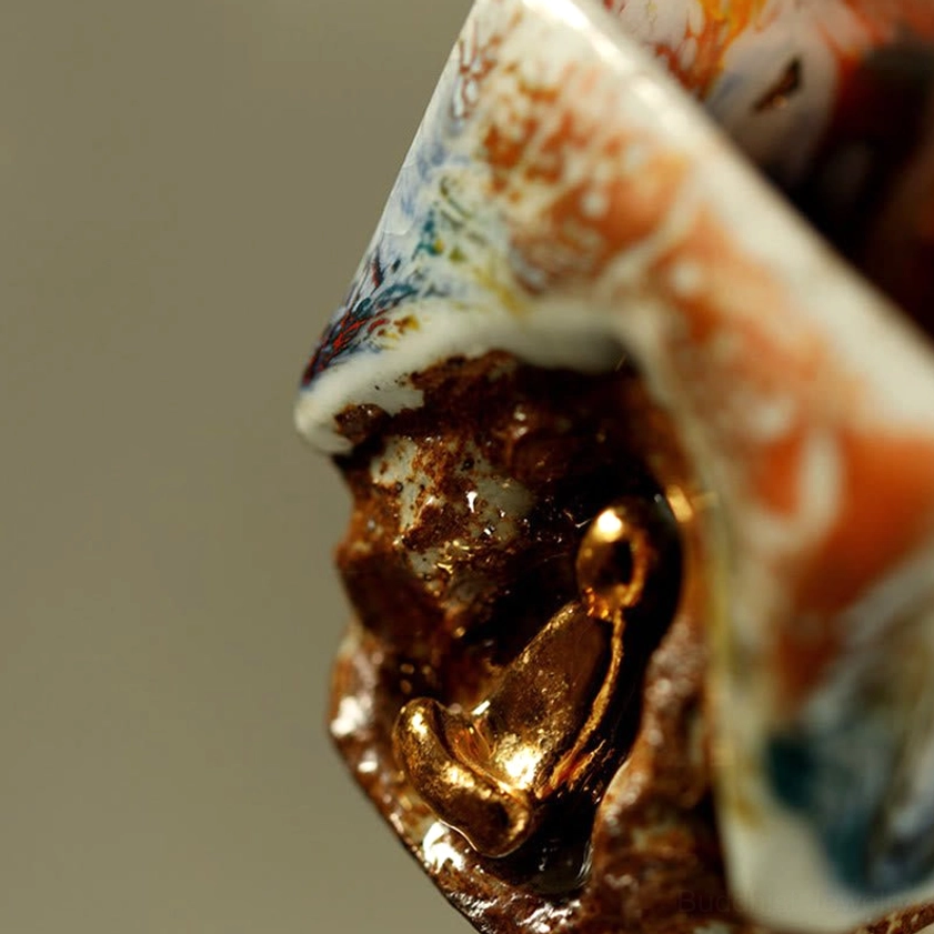 Macro close-up of Dunhuang teacup showing detailed gilded Buddha relief and thick layered glaze finish on neutral background